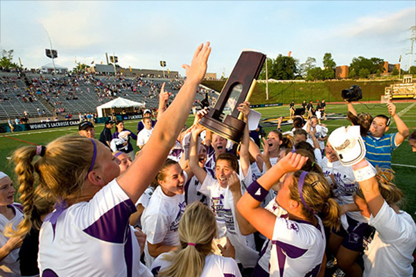 Lacrosse women holding a trophy and celebrating