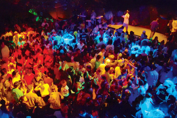 students dancing in a crowd with colorful lights shining on them