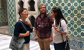 3 people in front of a green mosaic wall