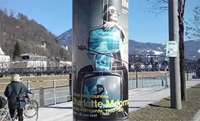 a poster on an advertising pillar announcing an art exhibit