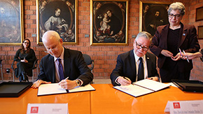 Two men signing an agreement, sitting at a desk