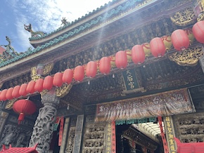 Entrance of a traditional Taiwanese temple with ornate architectural details, including green-tiled roofs and dragon sculptures. 