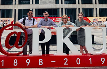 Four Northwestern staff members standing behind a Peking University sign