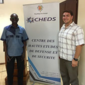 Two people pose with a sign advertising a military school