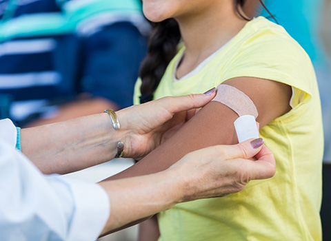 person getting a Band-Aid put on their arm by doctor