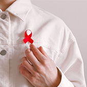 person in white jacket wearing red HIV/AIDS ribbon on