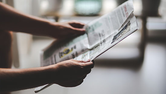 Hands holding a newspaper.
