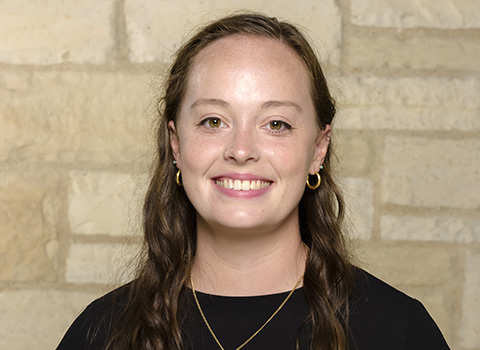 Claire Miller headshot in front of stone wall
