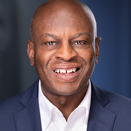 bald man in blue suit, white shirt, and blue tie, not smiling