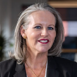 professional woman with grey hair smiling in a blue shirt
