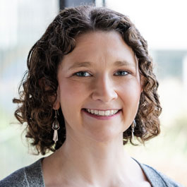 younger woman with curly brown hair smiling