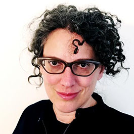 woman with curly black hair and glasses smiling