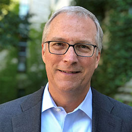 man with gray hair and glasses smiling