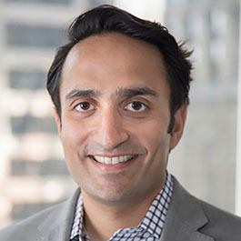 man with black hair in gray suit and checkered shirt