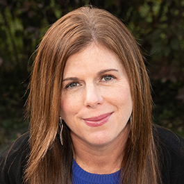 white woman with red hair and in a blue shirt smiling