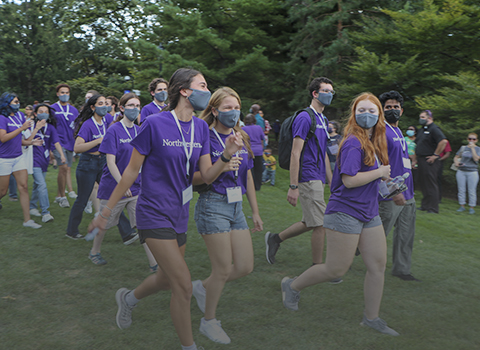 students walking onto Deering Meadow after March Thru the Arch