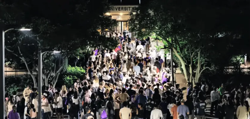 a crowd of student at a night time having fun on campus
