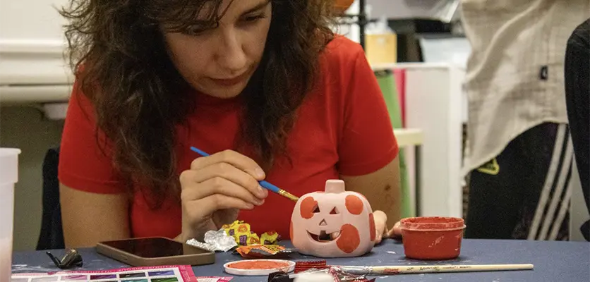 a woman decorating a pumpkin
