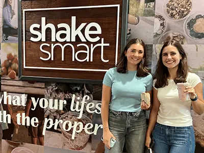 two girls holding milkshakes and sandwiches