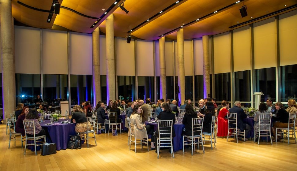 People sit around tables at a formal dinner event.