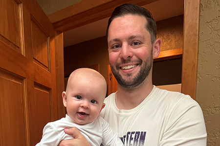 man smiling and holding baby