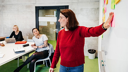 A professor points at a white board in class.