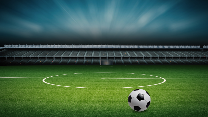 A soccer ball sits on a field in an empty stadium