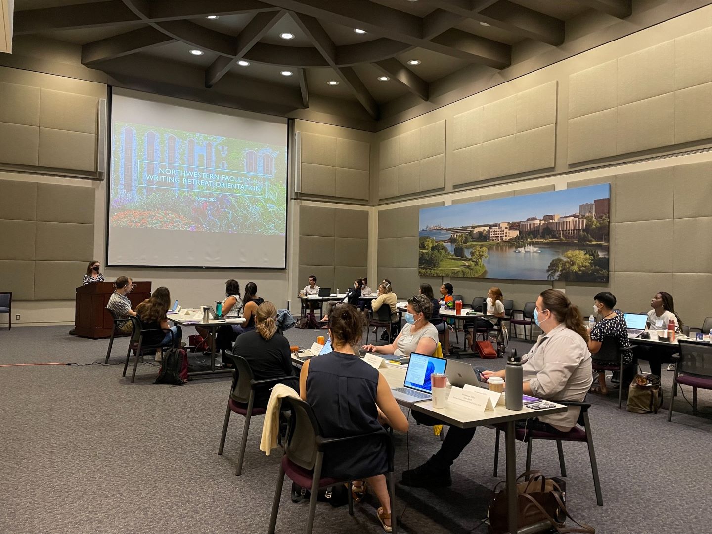 About 30 faculty members watch a presentation on white screen.