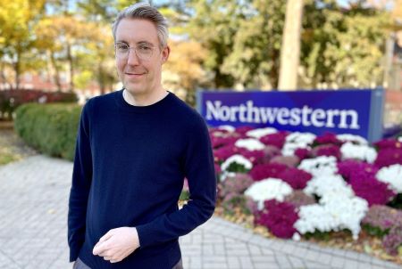 Michael Fitzpatrick smiles into the camera while standing in front of a Northwestern University sign.
