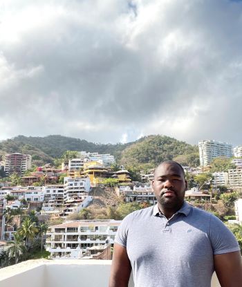 Norvell Watts stands in front of a tropical background.