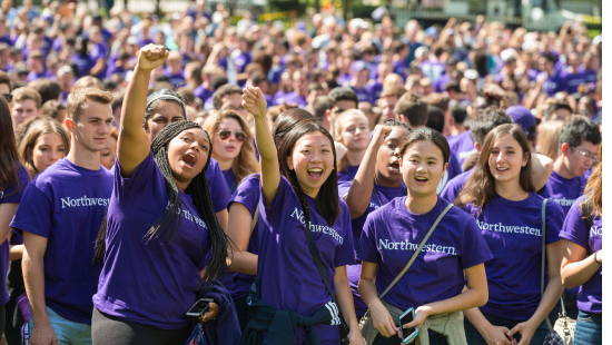 Crowd of students in Northwestern t-shirts cheering and smiling