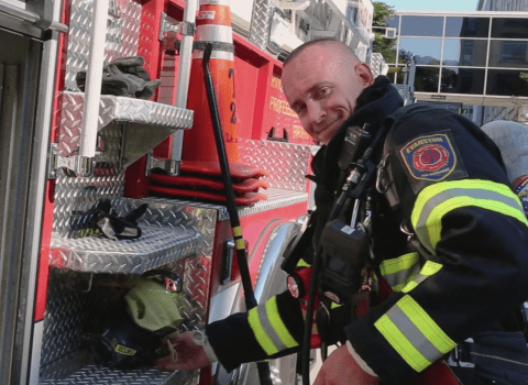 Smiling firefighter standing near his fire truck