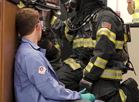 Firefighter tending to injured lab worker sitting on floor of lab