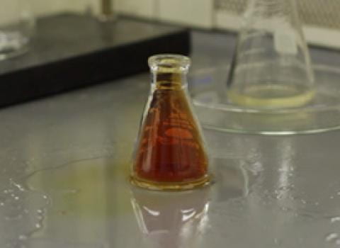 Small vial of nitric acid waste which has overflowed onto lab bench