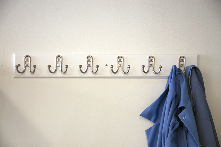 Two blue lab coats hanging on coat hooks