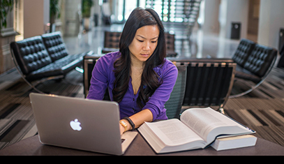 Grad student studying with a book and laptop.