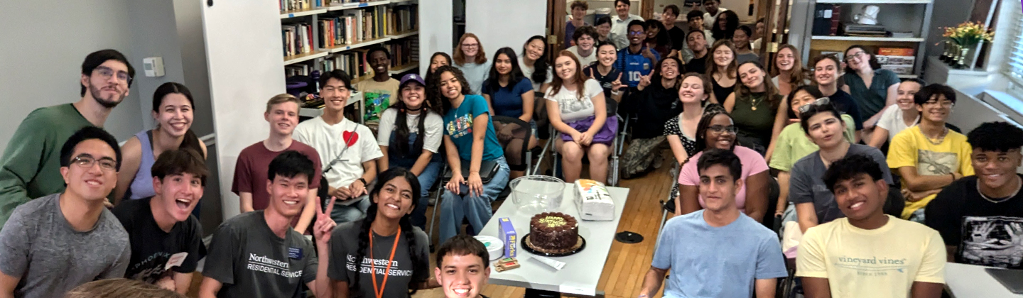 A group of students poses while sitting at a long table
