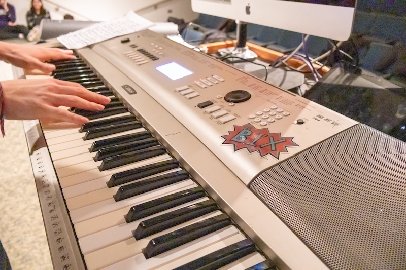 Two hands play a musical keyboard with a stick on it that says "The Bix"