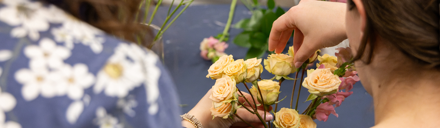 Students arrange yellow and pink flowers into a bouquet