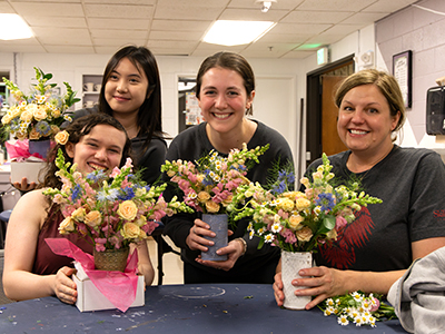 A group of students pose with their flower arrangements