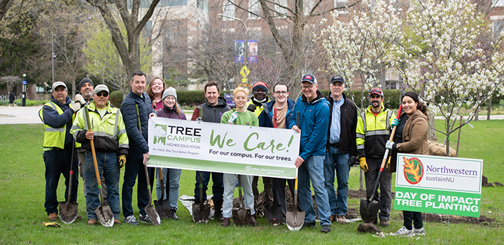 Staff outdoors together for a group photo at tree planting on campus.