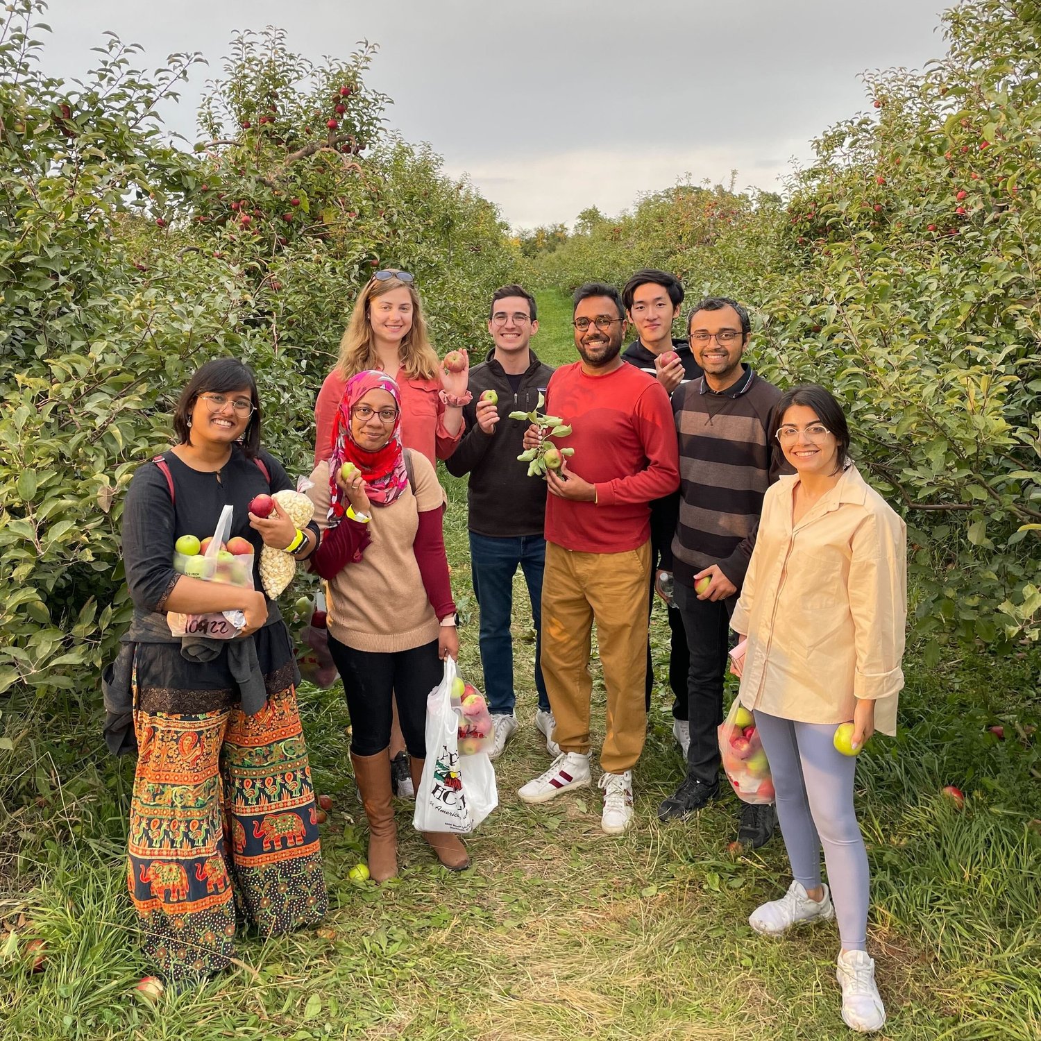 Members of the Goyal lab (8 in all) in an apple orchard smiling torwards the camera