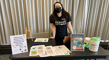 Student with a table full of compost information at an event.