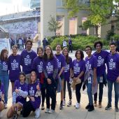 A group of Northwestern students in shirts that read "trash tacklers" stand in front of the football stadium.