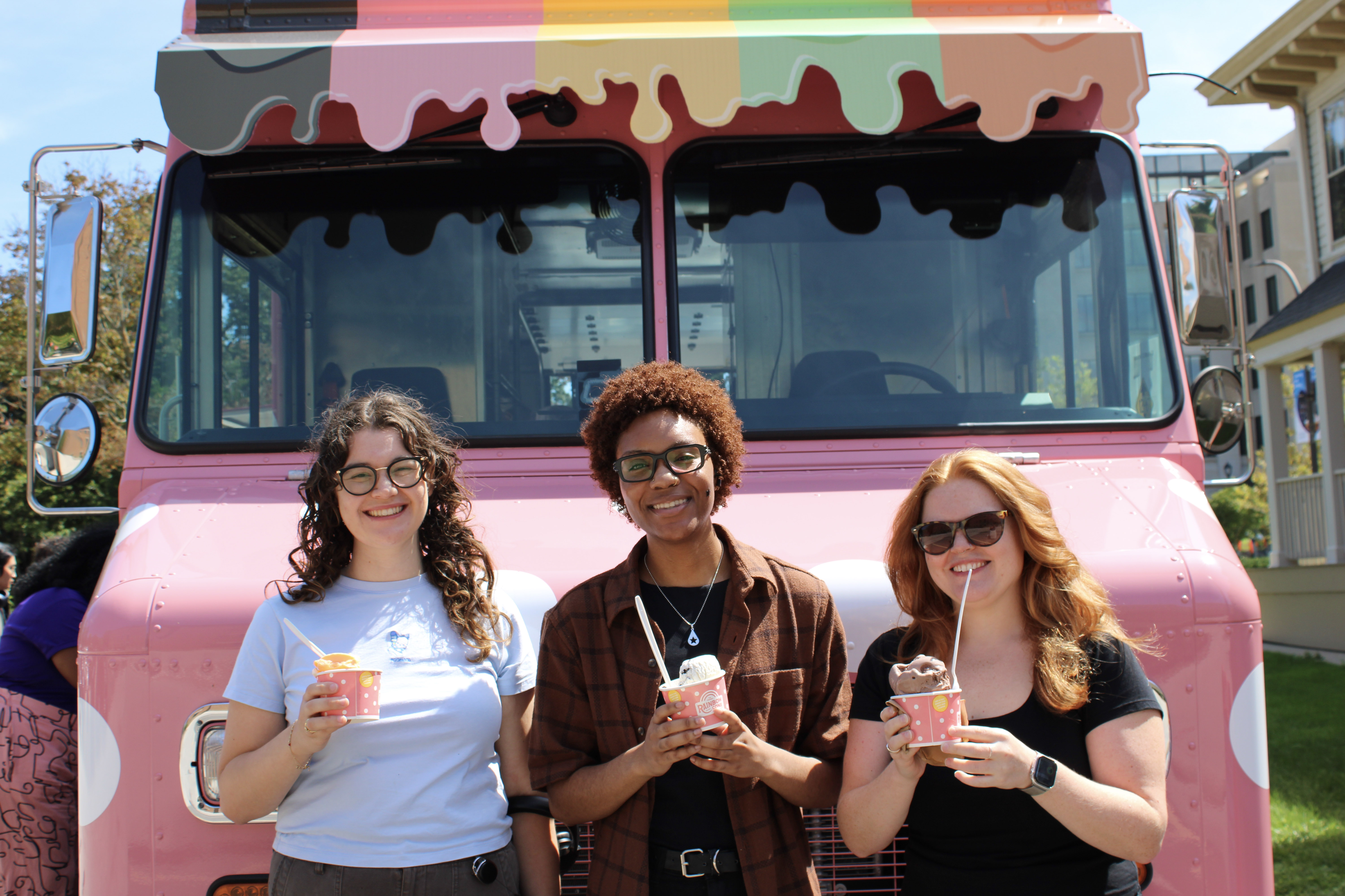 A group of students holding ice cream in front of the pink ice cream truck