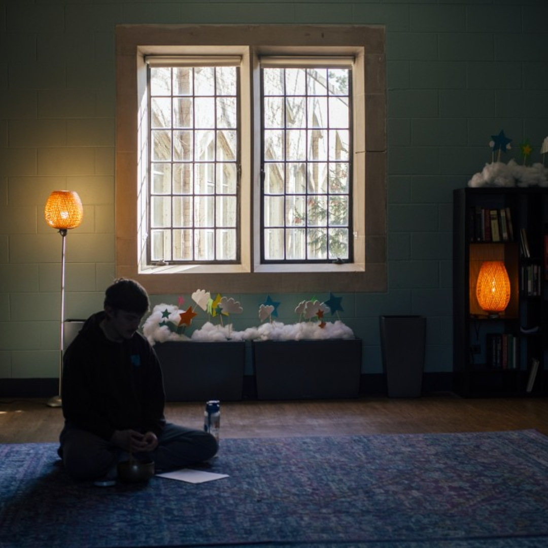 student meditating in dimly lit room